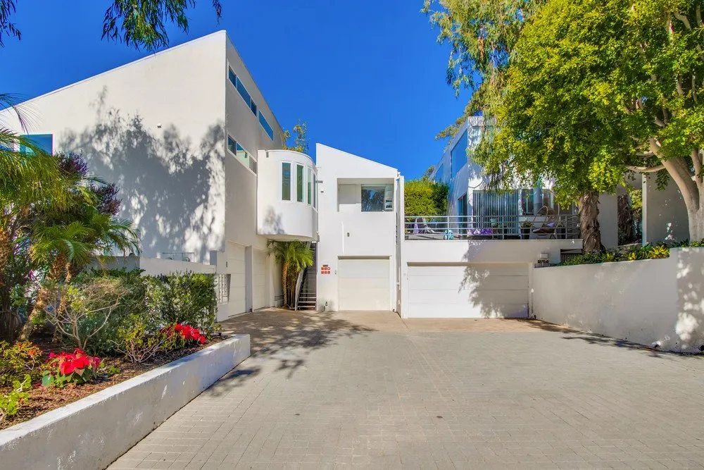 White modern multi-unit rental property with garages and a landscaped paver driveway in San Diego